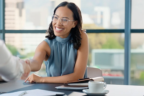 Eine junge Frau, die in einem modernen Büro eine professionelle Begrüßung durchführt und dabei freundlich und zugewandt wirkt