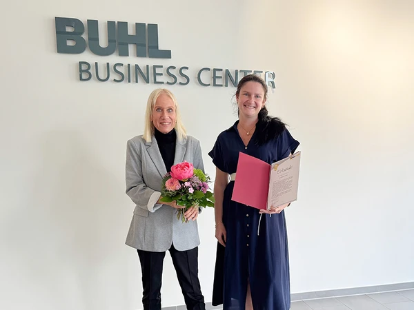 Unsere Chefredakteurin Karoline Giokas freute sich über den schönen Blumenstrauß zum Jubiläum. Gemeinsam mit Daniela Müller strahlt sie in die Kamera.