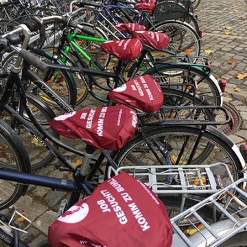 Münster wird BUHL-rot! 1000 Fahrradsattel-Schoner mit der Kochmütze wurden vor kurzem vor der Uni in Münster verteilt